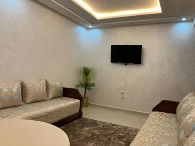 a living room with a couch and a flat screen tv at Appartement lumineux près de la plage de Sidi Bouzid in El Jadida