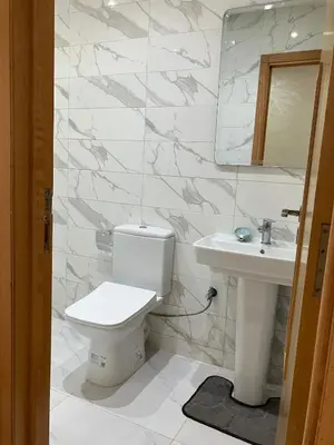 a white bathroom with a toilet and a sink at Appartement lumineux près de la plage de Sidi Bouzid in El Jadida
