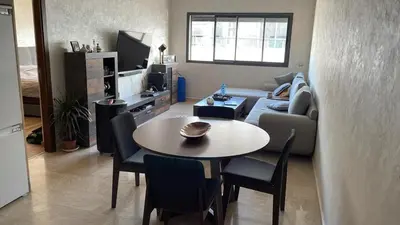 a living room with a table and a couch at Appartement Ferme Bretonne en face de l'OCP - 2 Min CFC in Casablanca
