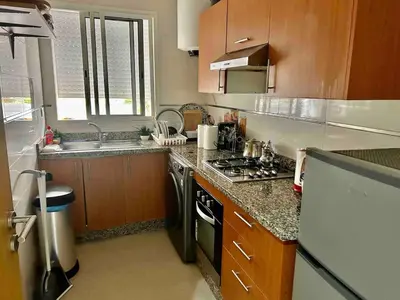 a kitchen with wooden cabinets and a stove top oven at Vivez le Confort Moderne et la Serennité in Rabat