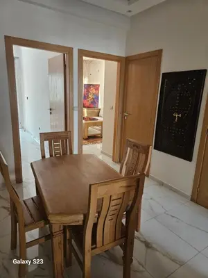 a dining room with a wooden table and chairs at Appartement Harhoura La vallée pas loin de Arzana hotel in Temara