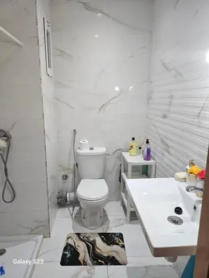 a white bathroom with a toilet and a sink at Appartement Harhoura La vallée pas loin de Arzana hotel in Temara