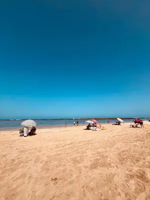 people on a beach with umbrellas and the ocean at Appartement Skhirat , vue sur mer in Skhirat