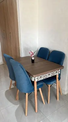 a dining table with blue chairs and a wooden table at appartement de lux vue piscine 5 min plage bouznika in Bouznika