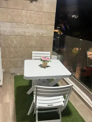 a white table with two chairs and a pot of flowers at appartement de lux vue piscine 5 min plage bouznika in Bouznika