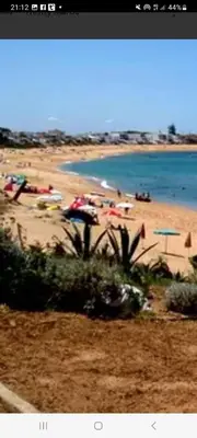 a beach with umbrellas and people on the beach at appartement de lux vue piscine 5 min plage bouznika in Bouznika