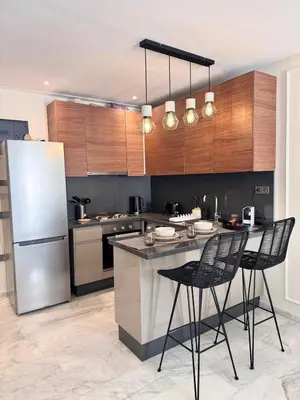 a kitchen with a refrigerator and a counter with chairs at Central Maarif Studio in Casablanca