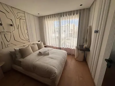 a white bed in a room with a large window at Comfortable & Central Casablanca Apartment in Casablanca