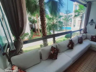 a white couch in a room with a large window at Appartement vue piscine à 3min de la plage bouznika in Bouznika