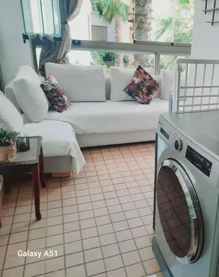 a living room with a couch and a washing machine at Appartement vue piscine à 3min de la plage bouznika in Bouznika