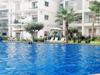 a swimming pool in front of a building at Appartement vue piscine à 3min de la plage bouznika in Bouznika