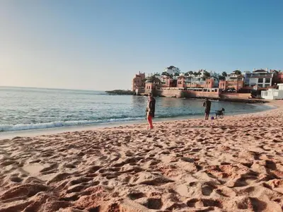 a group of people standing on a beach at Appartement vue piscine à 3min de la plage bouznika in Bouznika