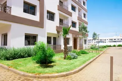 an apartment building with a courtyard with a palm tree at Les jardins d'Atlantis Dar Bouazza in Tamaris