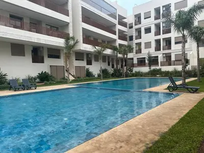 a large swimming pool in front of a building at Évasion luxueuse avec piscine proche de la mer in Mohammedia