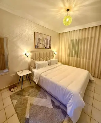 a bedroom with a large white bed and a chandelier at Apartment Majorelle Garden in Casablanca