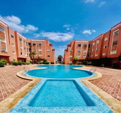a large swimming pool in a courtyard with buildings at logement entier familly house in Tamaris