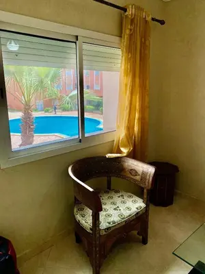 a chair in front of a window with a view of a pool at logement entier familly house in Tamaris