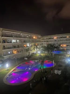 an apartment building at night with a swimming pool at Les jardins de bouznika in Bouznika