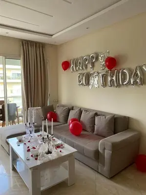 a living room with a couch and a table with a happy birthday sign at Les jardins de bouznika in Bouznika
