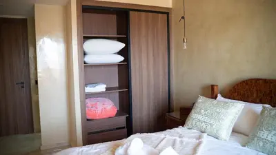 a bedroom with a bed and a shelf with towels at Nafhat al arz - Moroccan and refined in Mohammedia