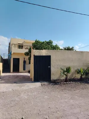 a building with a black door in front of a house at Dar Isa in Sidi Rahal