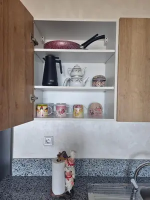 a kitchen counter with shelves with cups and dishes at Studio Zen vue sur mer in Aïn Harrouda