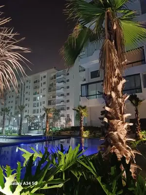 a hotel with a palm tree in front of a building at Studio Zen vue sur mer in Aïn Harrouda