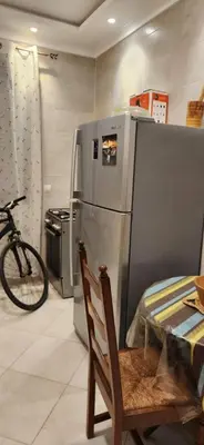 a kitchen with a refrigerator and a chair and a bike at appartement el Mansouria Sable d'or in O Ben Slimane
