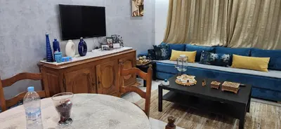 a living room with a blue couch and a table at appartement el Mansouria Sable d'or in O Ben Slimane
