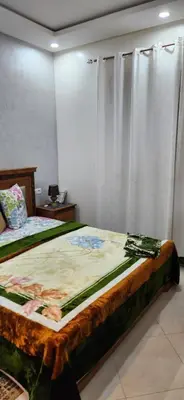 a bedroom with two beds and a window with curtains at appartement el Mansouria Sable d'or in O Ben Slimane