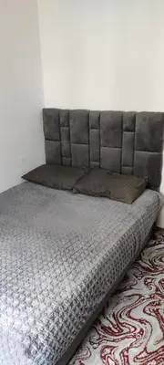 a bed with a gray headboard in a room at Calme absolu in Aïn Harrouda
