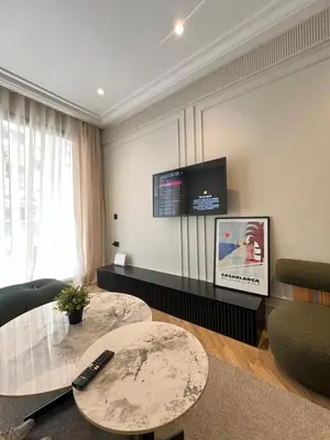 a living room with a table and a tv on the wall at Appartement Le Claridge in Casablanca