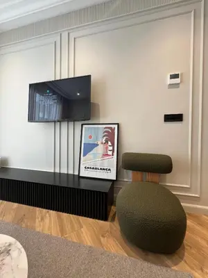 a living room with a chair and a flat screen tv at Appartement Le Claridge in Casablanca