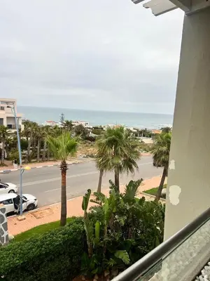 a view of a street with palm trees and the ocean at Appartament Melrose beach dar bouazza in Tamaris