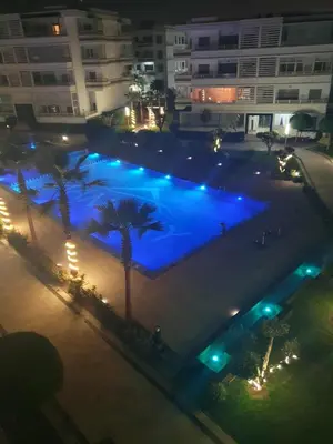 a large pool with blue lights in front of a building at Apparemment haut standing Mansbay in Mohammedia