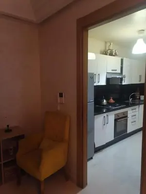 a living room with a chair and a kitchen at Apparemment haut standing Mansbay in Mohammedia