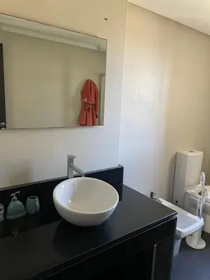 a bathroom with a white bowl sink on a black counter at Cozy beach house in Skhirat