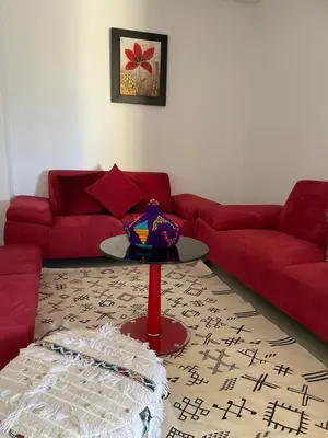 a living room with a red couch and a table at Cozy beach house in Skhirat