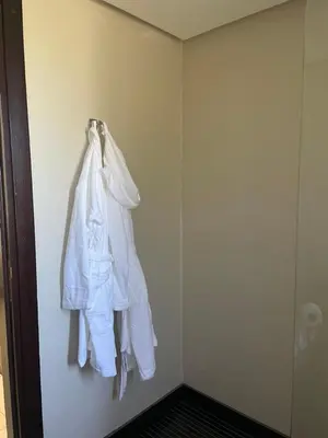 a white robe hanging on a wall in a bathroom at Cozy beach house in Skhirat