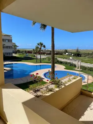 a view of a swimming pool with a palm tree at Cozy beach house in Skhirat