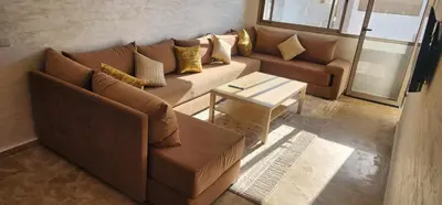 a living room with a brown couch and a table at Belle Appartent Vue Piscine A Malaga Beach A Mansouria in Mansouria