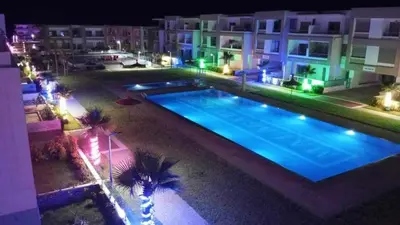 a large swimming pool with palm trees next to a building at Belle Appartent Vue Piscine A Malaga Beach A Mansouria in Mansouria