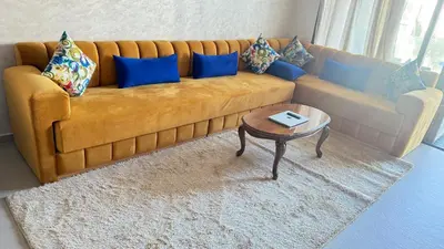 a living room with a couch with blue pillows and a table at luxury apartement en el mansouria in Pont Blondin