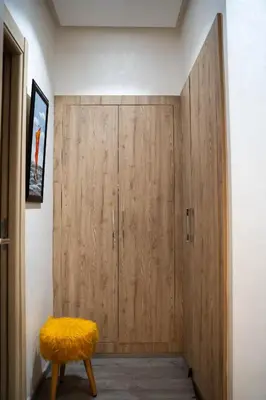 a room with a wooden door with a yellow stool at Charmante Deux Chambres et Salon Avec Jardin et Piscine à coté de plage in Casablanca