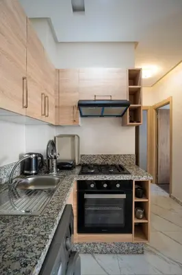 a kitchen with a stove and a sink at Charmante Deux Chambres et Salon Avec Jardin et Piscine à coté de plage in Casablanca