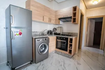 a kitchen with a stainless steel refrigerator and a dishwasher at Charmante Deux Chambres et Salon Avec Jardin et Piscine à coté de plage in Casablanca