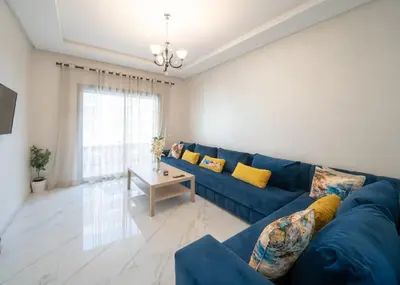 a living room with a blue couch and a table at Charming Studio for Rent with Pool Access & Kids Playground in Casablanca