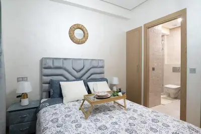 a bedroom with a bed with a table on it at Appartement 2 Chambres à Coté avec Grand Balcon, Piscine, Aire de Jeux pour Enfants et Jardin in Casablanca