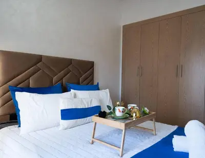 a bed with blue and white pillows and a table at Studio Confortable avec Balcon, Piscine, Jardin et Aire de Jeux in Casablanca