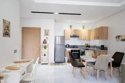 a kitchen with a table and chairs and a refrigerator at Studio Confortable avec Balcon, Piscine, Jardin et Aire de Jeux in Casablanca